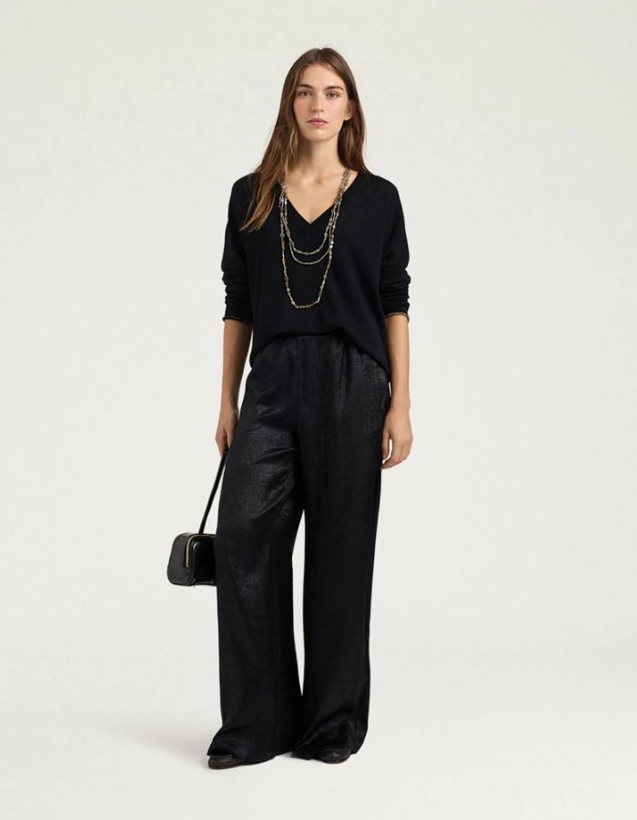 Silhouette avec le Pull pour femme en pure laine noire, modèle Astrid de la marque MOMONI. Présente une maille teinté en pièce et de délicates bordures en lurex doré aux finitions.