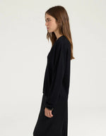 Profil du Pull pour femme en pure laine noire, modèle Astrid de la marque MOMONI. Présente une maille teinté en pièce et de délicates bordures en lurex doré aux finitions.