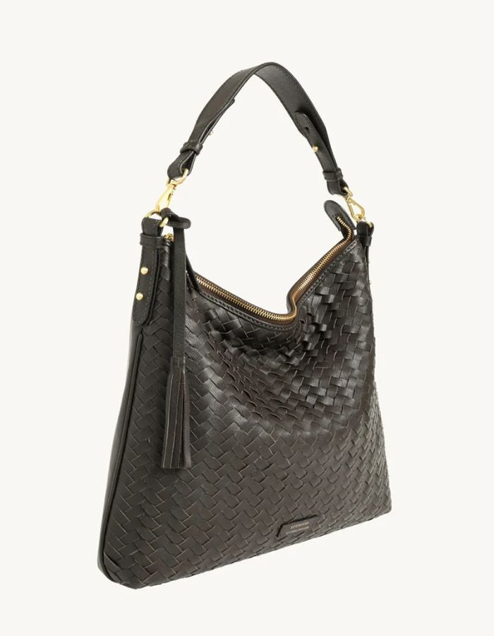 Profil du Sac hobo pour femme en cuir de vachette tressé marron chocolat avec pompon assorti, modèle Sharon de LOXWOOD. Porté épaule avec fermeture zippée.