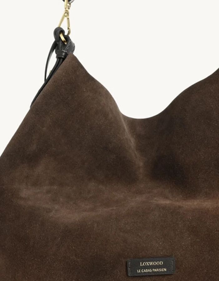 Vue de face du Sac hobo pour femme en cuir velours marron chocolat avec pompon assorti et porté épaule, modèle Sharon de la marque Loxwood.