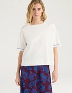 Vue de face du T-shirt oversize à manches courtes pour femme en jersey de coton blanc lurex, modèle Iora de la marque MOMONI. Présente une encolure ronde et de petites fentes latérales.