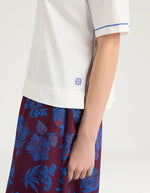 Manche du T-shirt oversize à manches courtes pour femme en jersey de coton blanc lurex, modèle Iora de la marque MOMONI. Présente une encolure ronde et de petites fentes latérales.