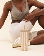 Photo d'ambiance avec le Grand mug isotherme 900ml couleur beige lin avec motif graphique Allure, poignée, paille en inox et embout silicone, modèle Travel Cup de la marque QWETCH