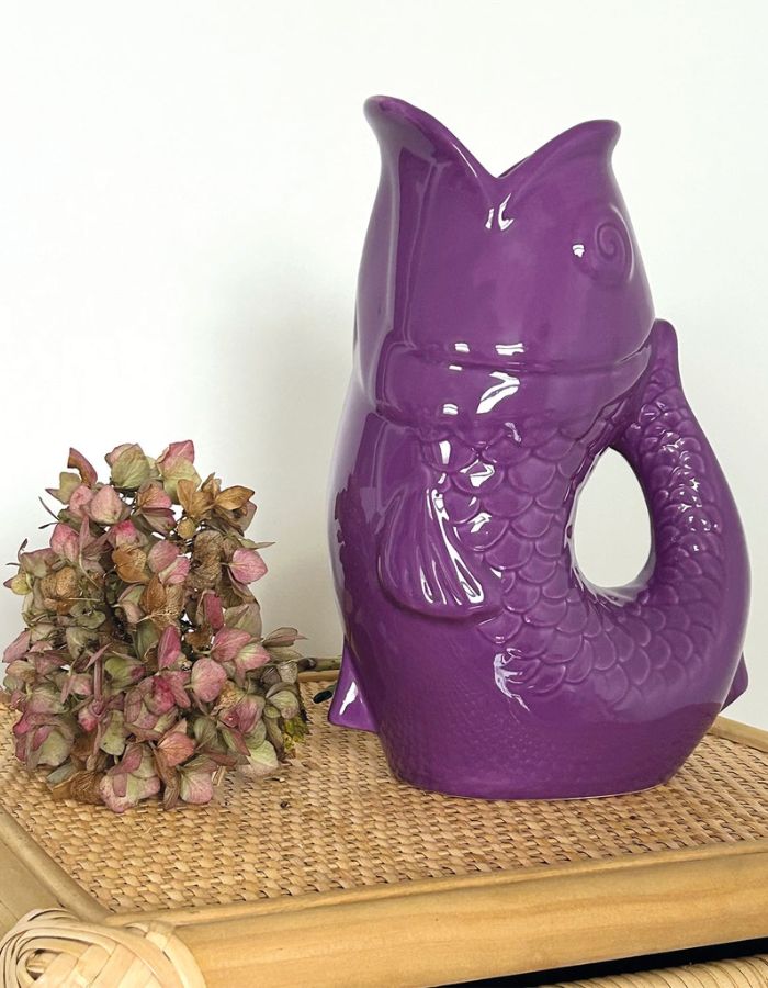Ambiance déco avec le Vase pichet poisson en faïence violette brillante, marque Opjet. Silhouette sculpturale rétro des années 60, hauteur de 25,3 cm, utilisable comme carafe ou vase.