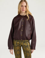 Vue de face de la Veste bomber courte pour femme en cuir d'agneau marron, modèle Kaldor de la marque MOMONI. Présente une coupe carrée avec cordon de serrage au bas et des boutons-pression en laiton vieilli.