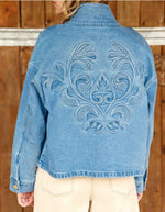 Dos de la Veste courte en jean bleu stone pour femme avec col montant et broderie en relief dans le dos, modèle Velmo de La Petite Étoile. Présente des poches à rabat et une coupe droite.