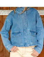 Silhouette avec la Veste courte en jean bleu stone pour femme avec col montant et broderie en relief dans le dos, modèle Velmo de La Petite Étoile. Présente des poches à rabat et une coupe droite.