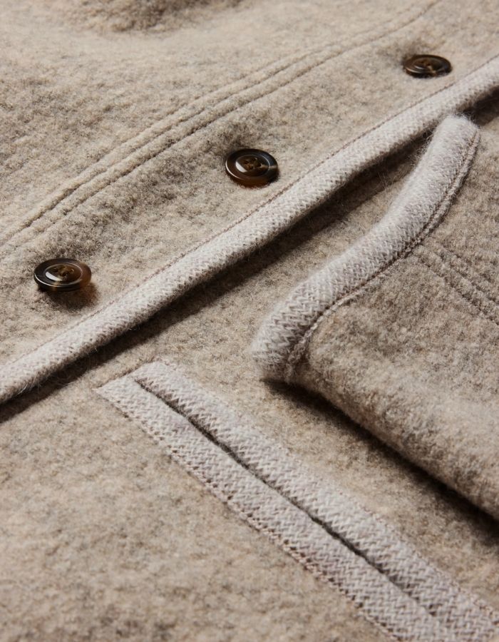 Détail de finition de la Veste courte autrichienne pour femme en laine bouillie beige et grise avec col montant, finitions gansées par une tresse et volume ample, modèle Olympe de la marque Soeur.