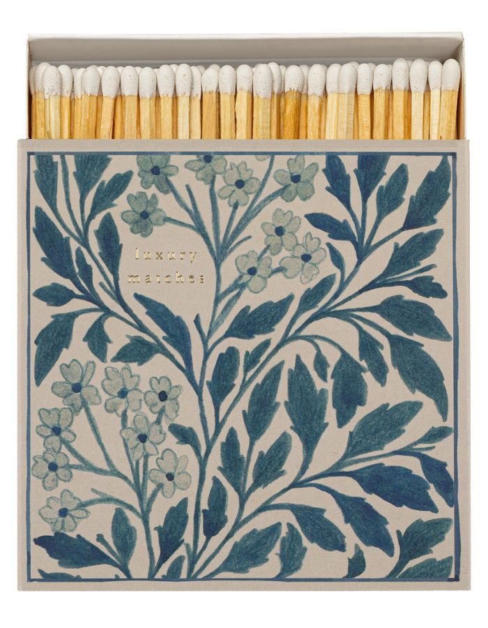 Grande boîte d'allumettes carrée ouverte de la marque Archivist au design floral bleu et blanc vintage avec l'inscription gravée en lettres dorées 'Luxury Matches'. À côté, le tiroir blanc est entrouvert, laissant apparaître de longues allumettes en bois naturel à tête blanche.