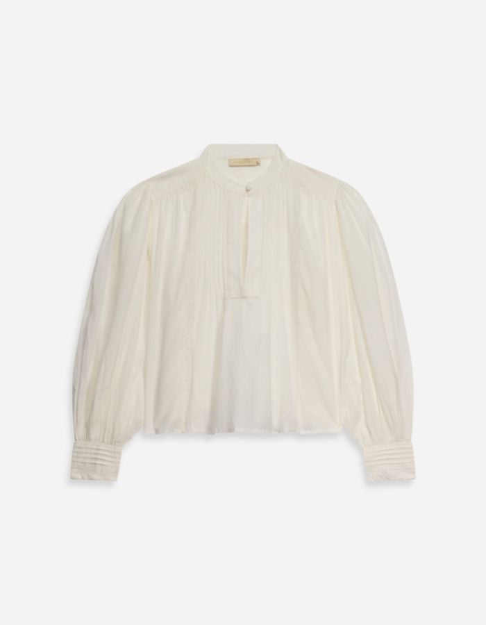Blouse blanche Gania en voile de coton avec col officier, encolure fendue, et manches bouffantes.