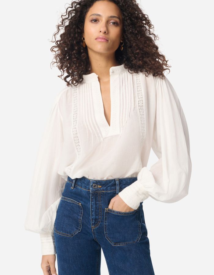 Blouse blanche Gania en voile de coton avec col officier, empiècements plissés et manches bouffantes.