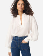 Blouse blanche Gania en voile de coton avec col officier, empiècements plissés et manches bouffantes.