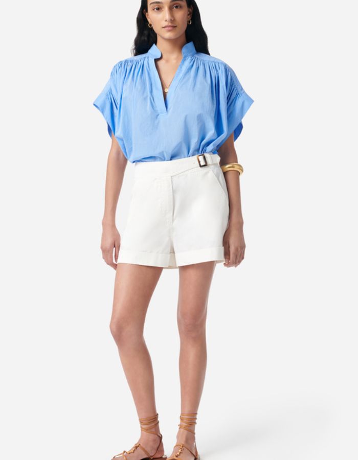 Blouse Cory Bleuet en coton, manches courtes, encolure en V, coupe ample, portée avec un short blanc.