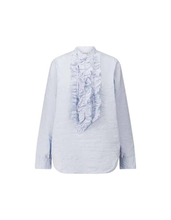 Blouse fluide bleu ciel en coton pour femme avec col officier, manches longues froncées et fermeture boutonnée sous volant, modèle Carita Light Blue de la marque Laurence Bras.