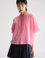 Blouse Dahlia Geranium rose en voile de coton, coupe oversized, col mandarin et patte de boutonnage à volants.
