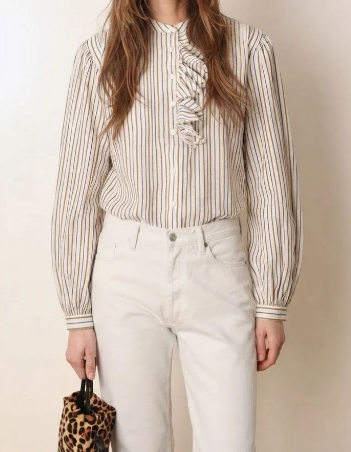 Silhouette avec la Blouse blanche ample en coton pour femme à rayures tissées avec col rond, manches bouffantes, plis plats et volants asymétriques sur le devant, modèle Fa de la marque Laurence Bras.