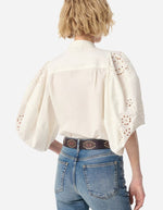 Blouse Felicie Ecrue en coton avec manches bouffantes à dentelle, portée avec un jean et une ceinture.