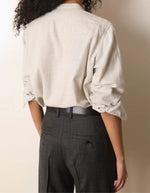 Dos e la Blouse fluide pour femme en coton beige off white, modèle Carita de la marque Laurence Bras. Présente un col officier, une fermeture boutonnée sous volant et des manches longues froncées.