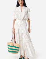 Blouse Ganu Blanche fluide et légère avec dentelle, manches volantées, portée avec jupe longue et sac en paille.