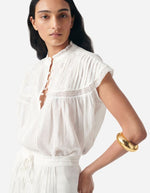 Blouse Ganu Blanche fluide et légère avec dentelle, fronces, encolure tunisienne et manches volantées.