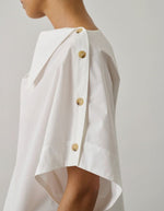 Blouse Issa Blanc Casse en coton biologique, coupe ample, col tombant et boutons à l'épaule.
