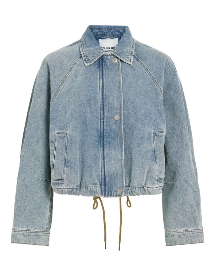 Blouson style bomber en jean pour femme de couleur bleu clair délavé Light Blue Denim, modèle Tiana de la marque Rouge Edit. Présente un col chemise évasé, une fermeture à glissière cachée sous des boutons-pression dorés mats Dull Gold et des brides de serrage ajustables.