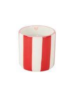 Gros plan sur la Bougie parfumée de créateur Chichou de la marque Opjet, présentée dans un pot cylindrique en céramique blanche de 8 cm de hauteur orné de rayures horizontales rouges peintes à la main.