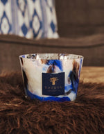Gros plan sur la Bougie parfumée en verre soufflé à la main aux motifs laiteux et bleu cobalt inspirés du lapis-lazuli.