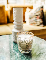 Photo d'ambiance avec la Bougie parfumée Aurum de la gamme My First Baobab par Baobab Collection. Verre décoré d'un logo graphique inspiré des années 1970. Parfum iconique au jasmin et musc.