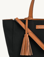 Gros plan sur le Sac cabas zippé pour femme en nylon satiné noir avec bandoulière amovible, modèle Cabas Parisien Zippé de la marque LOXWOOD. Présente des anses de porté main, un pompon décoratif et des finitions simili-cuir