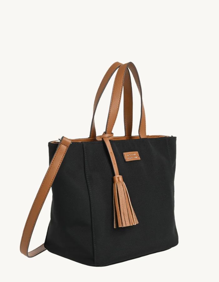 Profil du Sac cabas zippé pour femme en nylon satiné noir avec bandoulière amovible, modèle Cabas Parisien Zippé de la marque LOXWOOD. Présente des anses de porté main, un pompon décoratif et des finitions simili-cuir