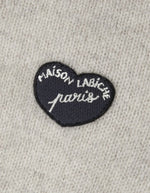 Patch poitrine sur le Cardigan droit boutonné en laine d'agneau couleur gris ciment pour homme avec patch cœur sur la poitrine, modèle Lhomme de la marque Maison Labiche.