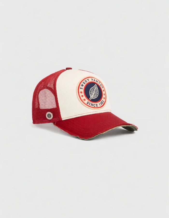 Vue de côté de la Casquette Trucker rouge Candy et blanche Home Run par Sweet Pants. Dotée du patch logo de la marque à l'avant, d'une visière rouge au fini usé sur la tranche et d'un filet de protection blanc respirant à l'arrière.