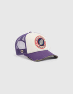Vue de côté de la Casquette Trucker bicolore Home Run par Sweet Pants, coloris violet Imperial et blanc. Patch logo de la marque cousu à l'avant, visière violette avec bordure effet usé et panneau arrière en maille filet blanc.