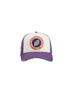 Casquette Trucker bicolore Home Run par Sweet Pants, coloris violet Imperial et blanc. Patch logo de la marque cousu à l'avant, visière violette avec bordure effet usé et panneau arrière en maille filet blanc.