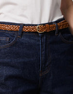 Gros plan sur la Ceinture fine pour femme modèle Avery de la marque Pieces, en cuir véritable tressé de couleur marron cognac avec une boucle métallique arrondie