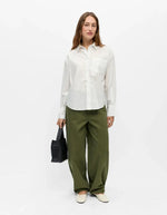 Silhouette portée avec la Chemise blanche à manches longues pour femme, modèle Zila de la marque Object. Tissu tissé en coton biologique et Tencel avec un imprimé discret sur toute la surface, poche poitrine et col classique.