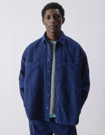 Vue de face de la Chemise en denim brut bleu foncé pour homme, modèle Comow de la marque American Vintage. Coupe ample et oversize, dotée de manches longues, de deux poches plaquées sur la poitrine et d'un col chemise classique. Au dos, le logo de la marque apparaît discrètement grâce à une finition gravée au laser