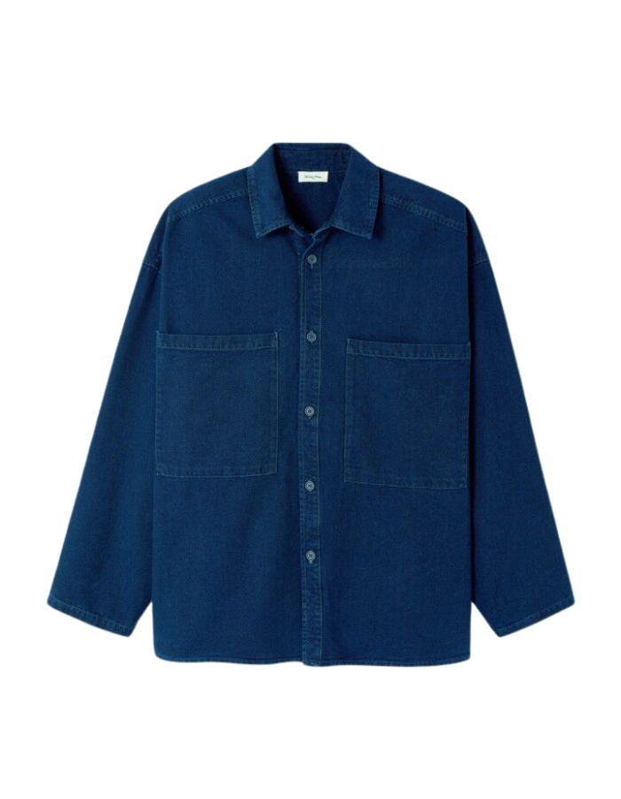 Chemise en denim brut bleu foncé pour homme, modèle Comow de la marque American Vintage. Coupe ample et oversize, dotée de manches longues, de deux poches plaquées sur la poitrine et d'un col chemise classique. Au dos, le logo de la marque apparaît discrètement grâce à une finition gravée au laser