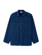 Chemise en denim brut bleu foncé pour homme, modèle Comow de la marque American Vintage. Coupe ample et oversize, dotée de manches longues, de deux poches plaquées sur la poitrine et d'un col chemise classique. Au dos, le logo de la marque apparaît discrètement grâce à une finition gravée au laser