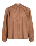 Chemise unie pour femme modèle Esma de la marque Vila. Coupe droite à manches longues en coton bio de couleur marron terracotta clair Nuthatch, caractérisée par un col officier élégant et une fermeture boutonnée.