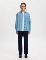 Homme portant une chemise en jean bleu clair Carlo, coupe regular, avec poche poitrine et boutons blancs.