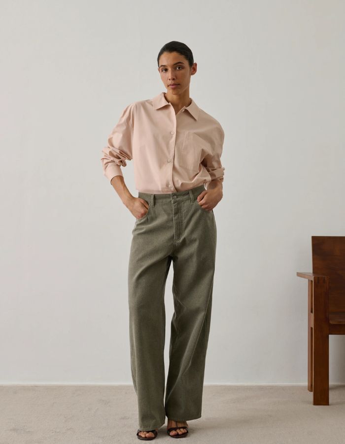 Femme portant une chemise ample rose blush en popeline de coton biologique avec poche poitrine.