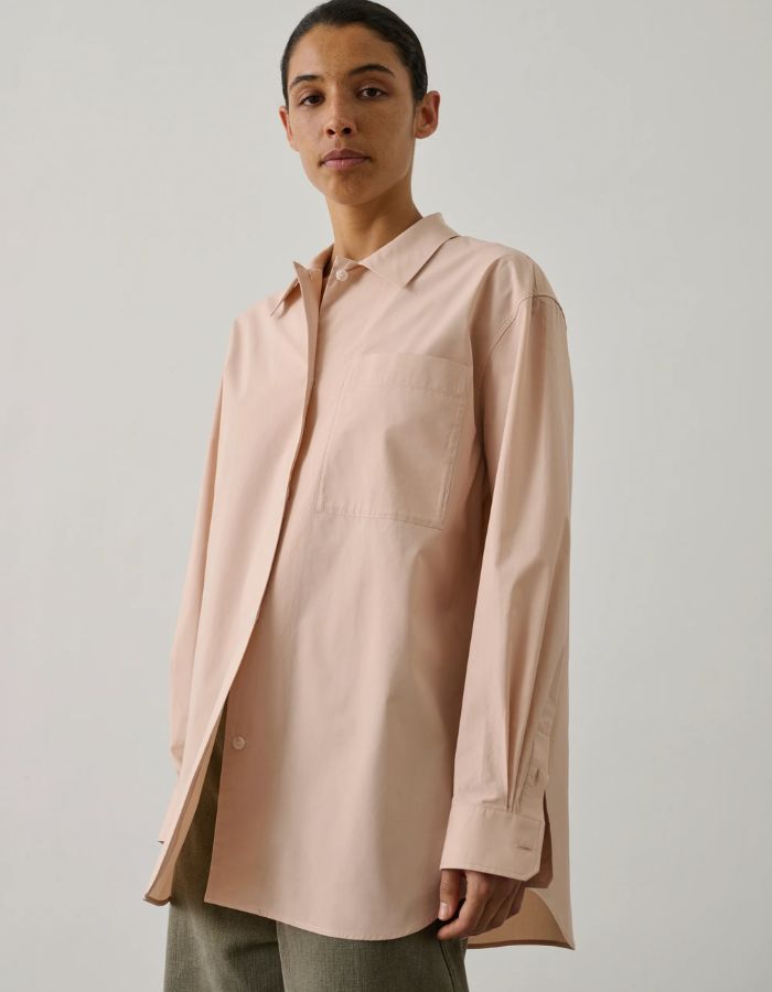 Femme portant une chemise ample rose blush en popeline de coton biologique avec col, boutonnage et poche poitrine.