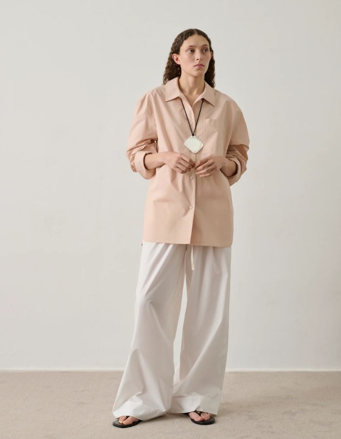Femme portant une chemise ample rose blush en popeline de coton biologique avec poche poitrine et bas liquette.