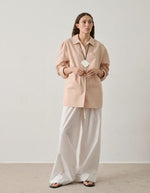 Femme portant une chemise ample rose blush en popeline de coton biologique avec poche poitrine et bas liquette.