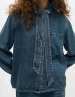 Devant de la Chemise en jean manches longues pour femme de couleur bleu moyen Medium Blue Denim, modèle Rosie de la marque Object. Confectionnée dans une toile de denim souple, elle présente un col chemise, une fermeture boutonnée, une poche plaquée sur la poitrine et un détail de nœud en tissu délicat.