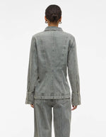 Dos d'une femme portant une chemise en denim gris clair à manches longues et coupe regular.