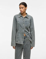 Femme portant une chemise en denim bleu clair Vivian avec col, boutons et poche poitrine.