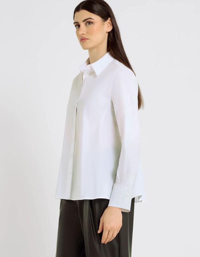 Profil de la Chemise évasée pour femme en popeline de coton stretch blanc optique, modèle Dorothea de la marque Hana San. Présente une coupe patineuse, une découpe au dos et des poignets plissés avec boutons en nacre.